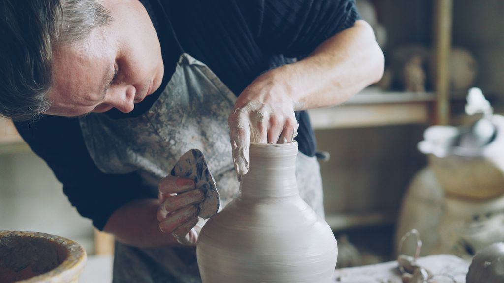 Artist skillfully shaping a clay pot on a pottery wheel in a studio setting.